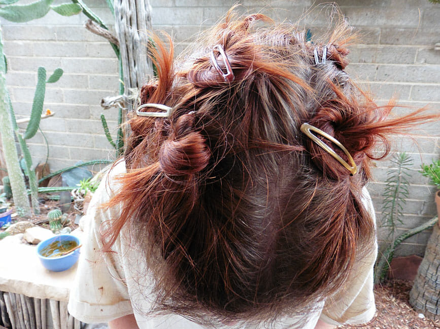 Photo of me with barrettes in my hair getting ready to henna my hair with Light Mountain Henna in red.