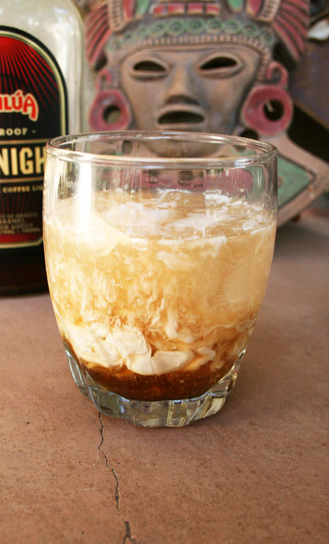 Close up of Vegan White Russian with Kahlúa Midnight Coffee Liqueur and Aztec mask in the background.