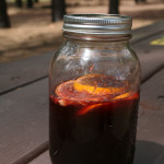 Camping Sangria in a mason jar on a picnic table in the forrest.