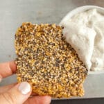 Everything Bagel Flax Cracker in hand with dip.