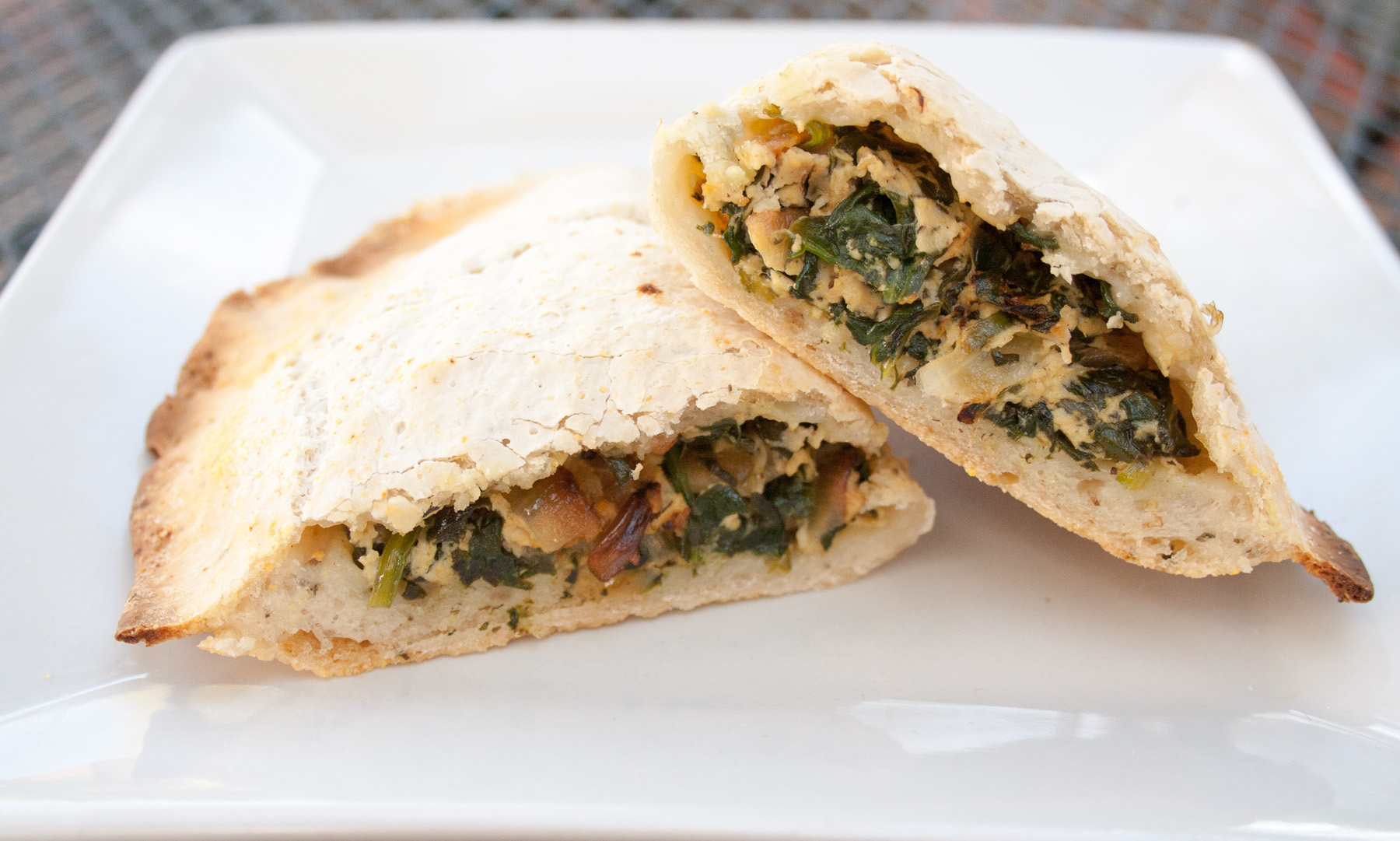 Spinach and Tofu Ricotta Calzones close up of a cut open calzone on a plate.