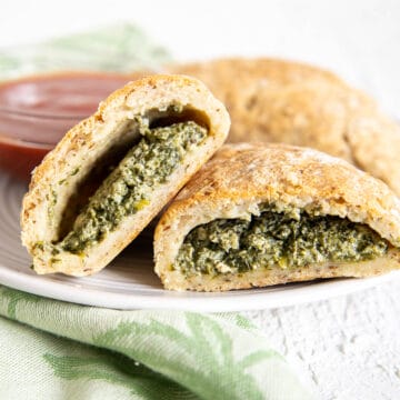 Spinach and Tofu Ricotta Calzones on a plate with marinara sauce.
