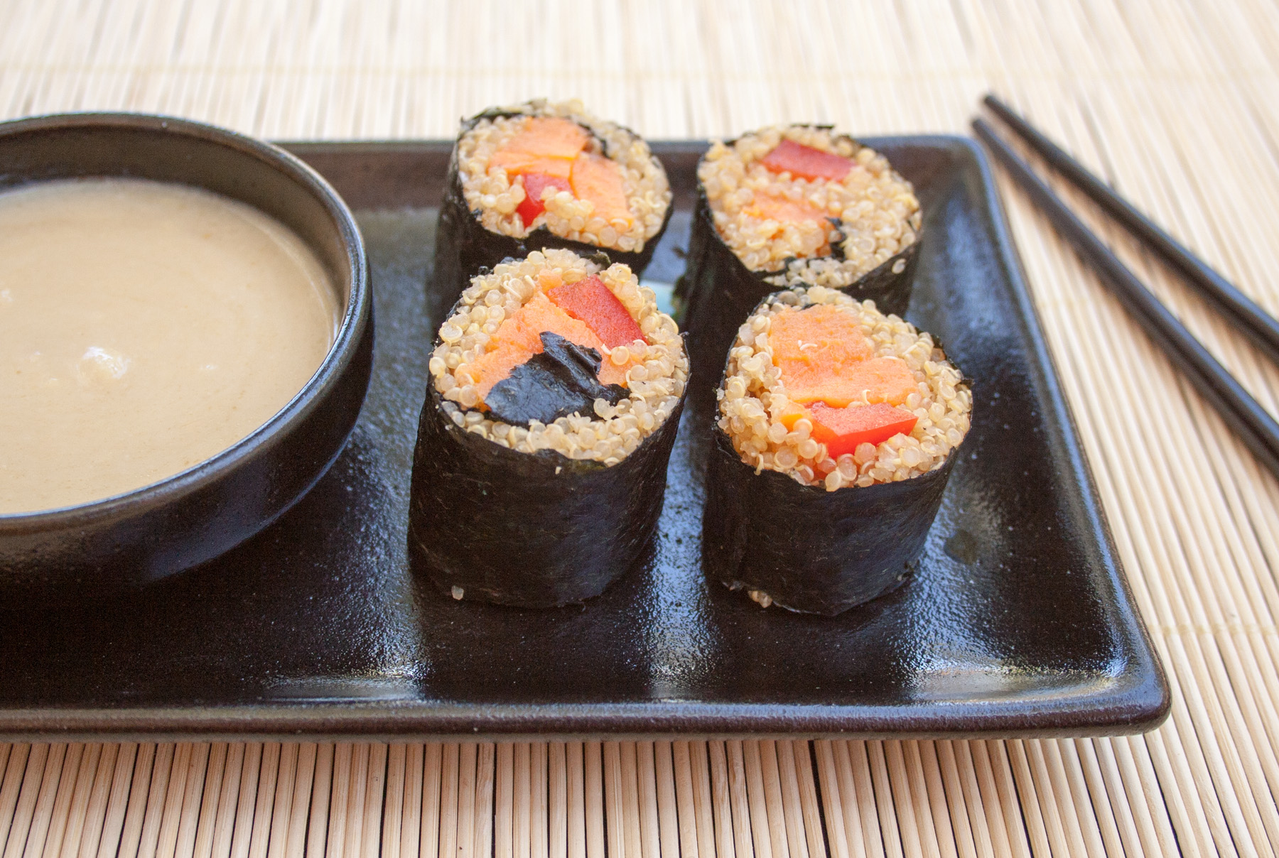 Sweet Potato Sushi Rolls on plate with sauce and chopsticks.