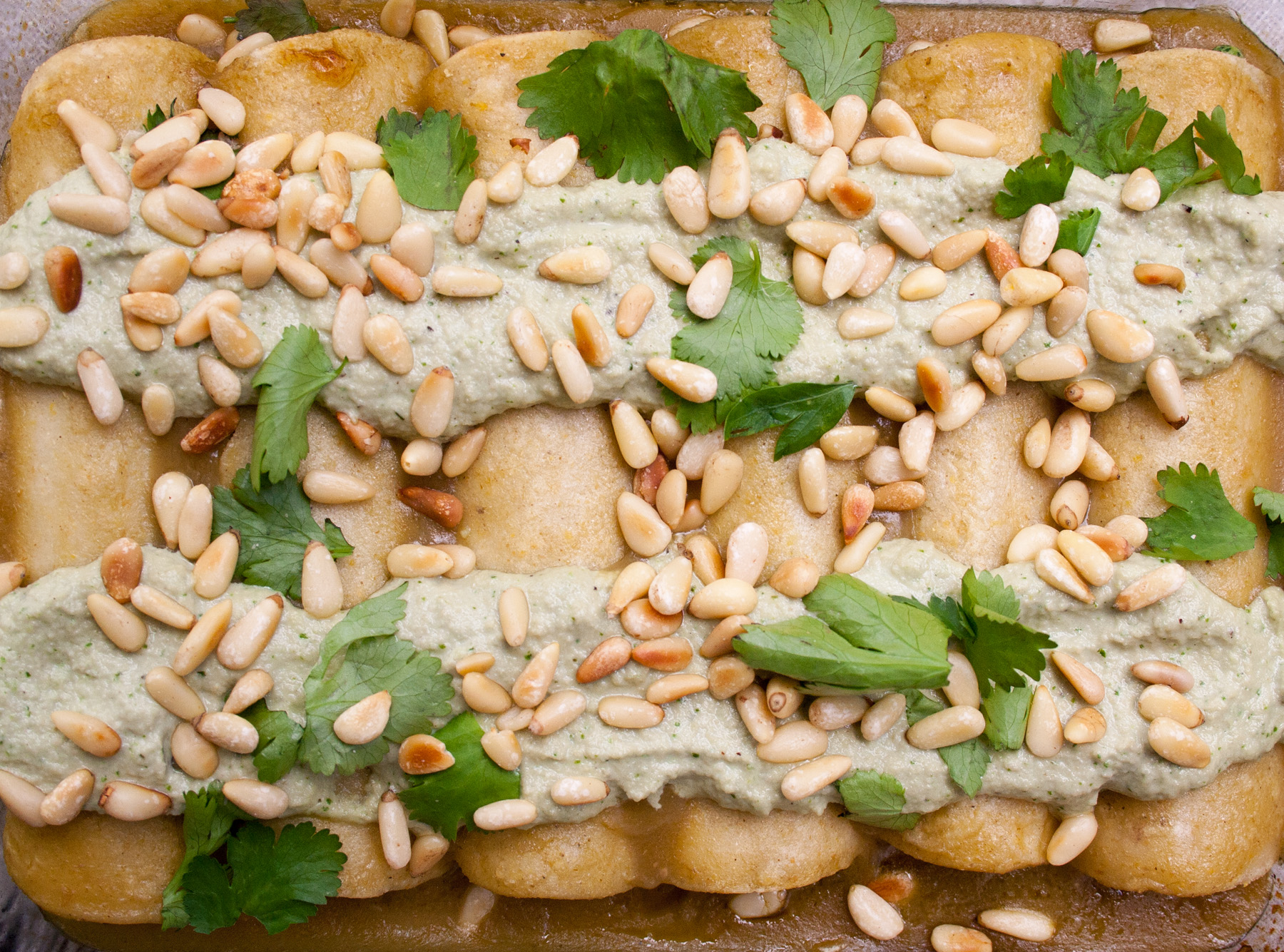 Spinach, Tofu, and Pine Nut Enchiladas birds eye view close up of enchiladas in baking dish.