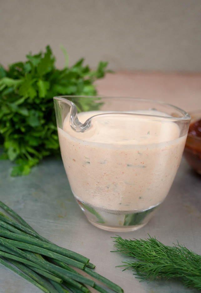 Vegan Chipotle Ranch Dressing vertical photo with herbs in the background.