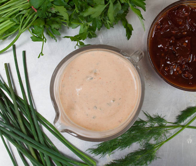 Vegan Chipotle Ranch Dressing horizontal with bowl of chipotle peppers and herbs surrounding dressing.