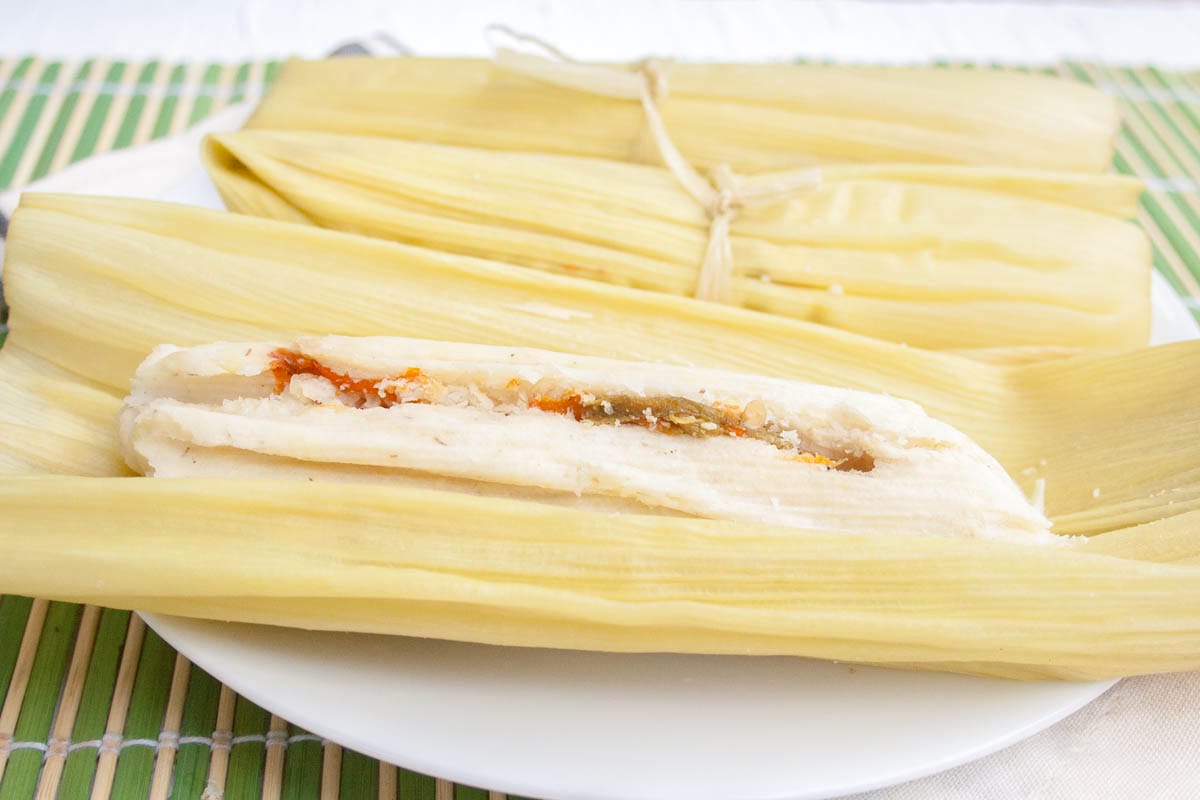 Vegan Green Corn Tamales (Tamales de Elote) - If you love Mexican food, then this recipe is for you! These rich, spicy tamales are made with Hatch green chiles, fresh white corn, and masa harina. (gluten free) Vegan Green Corn Tamales (Tamales de Elote) on a plate.