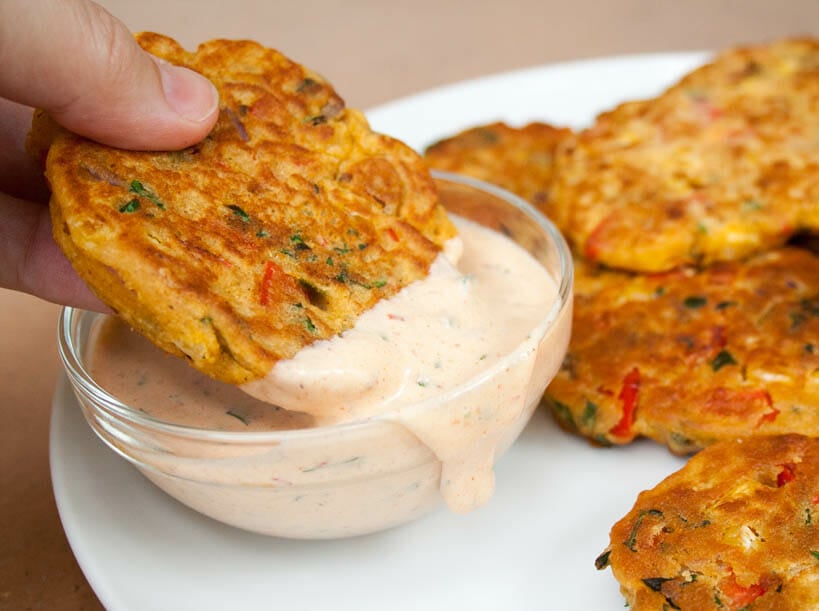 Vegetable fritter bring dipped into vegan chipotle ranch dressing.