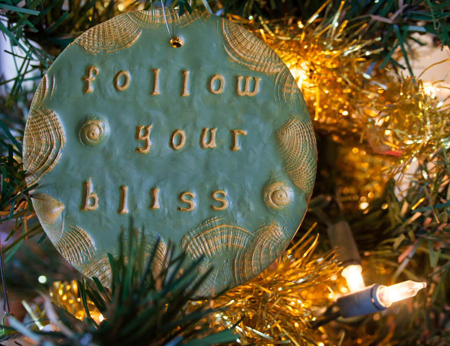  Follow Your Bliss polymer clay ornament hanging on artificial tree.