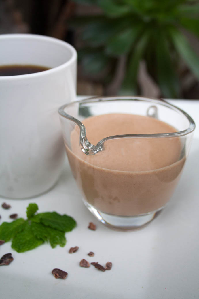 Mint Chocolate Coffee Creamer vertical with cup of coffee in the background.