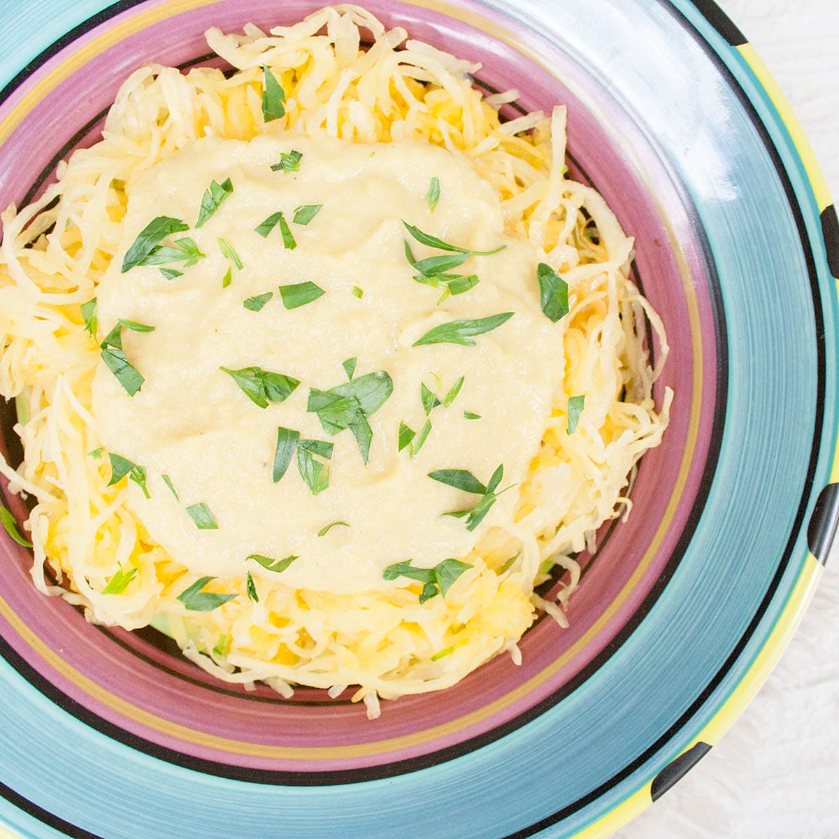 Vegan Cauliflower Alfredo Sauce on top of baked spaghetti squash on a plate.