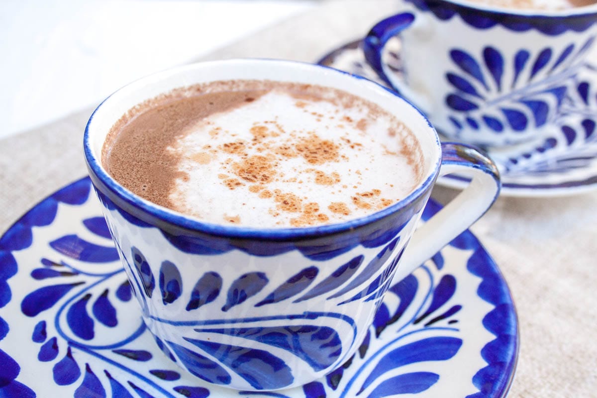 Vegan Mexican Hot Chocolate (gluten free) - This recipe has a deep, rich chocolaty flavor with hints of cinnamon, nutmeg, and cayenne pepper. Add a dollop of coconut whipped cream for even more indulgence! Vegan Mexican Hot Chocolate in two mugs.