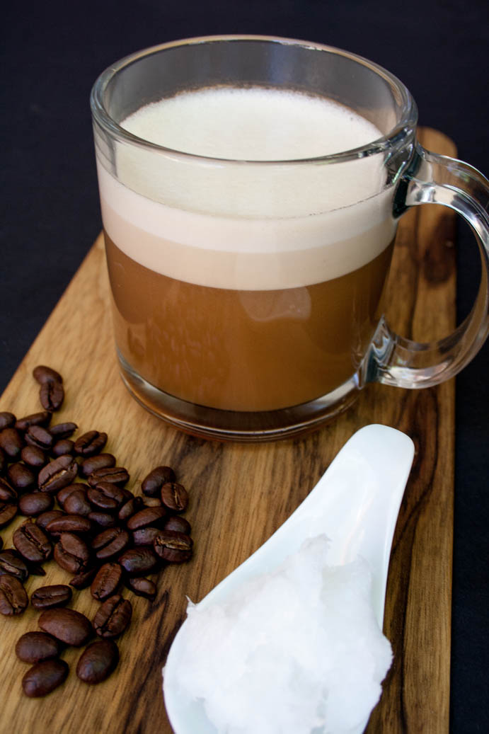 Vegan Bulletproof Coffee with coffee beans and a spoonful of coconut oil.