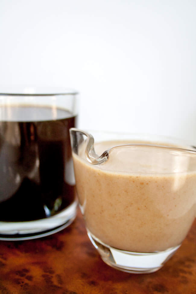 Caramel Coffee Creamer close up with a cup of black coffee in the background.