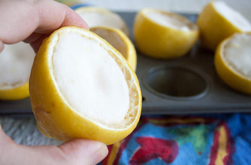 Lemon Fat Bomb being held up for a close up photo. More fat bombs in background sitting in a muffin tin.