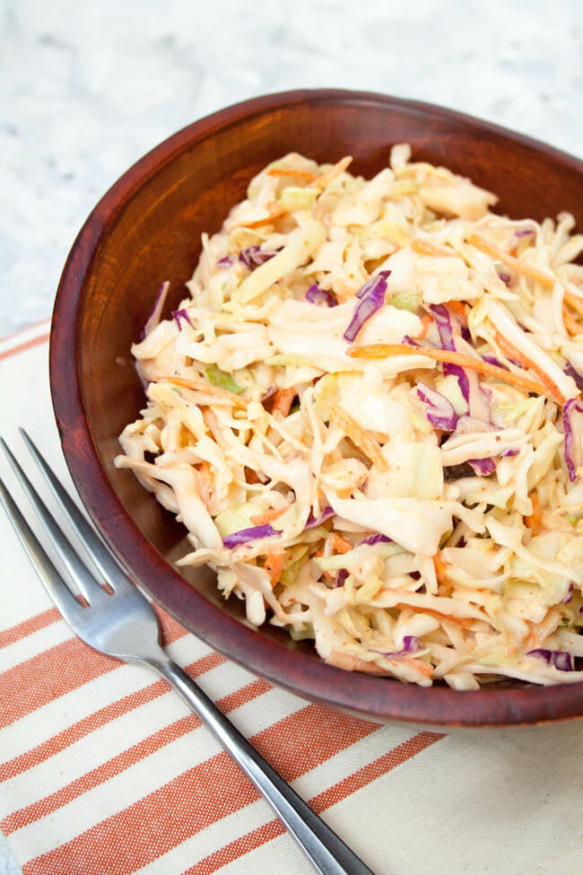 Sriracha Coleslaw in a wood bowl with fork.