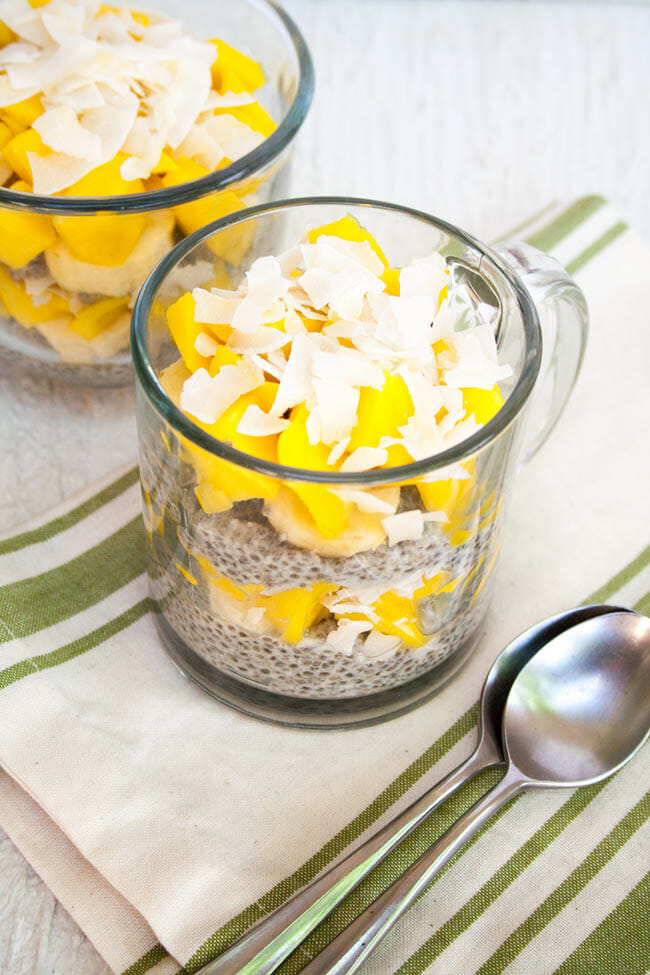 Tropical Chia Pudding in two glass mugs with spoons.