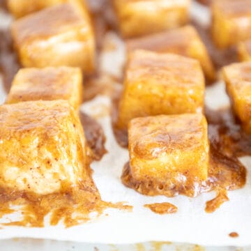 Baked tofu with peanut sauce on a parchment paper lined baking sheet.