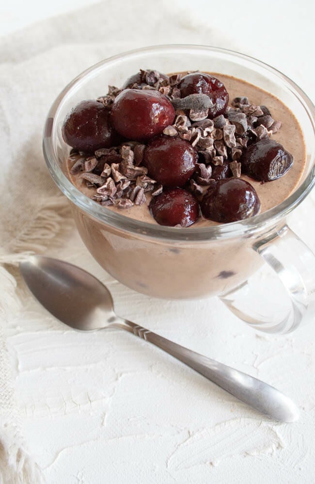 Chocolate Cherry Chia Pudding in glass mug with spoon.