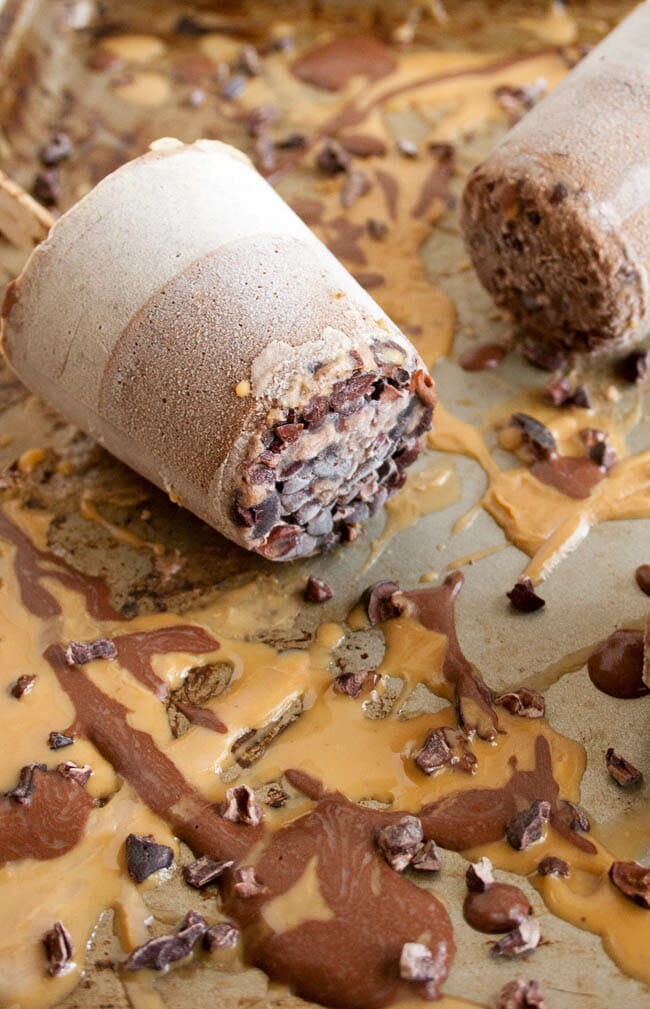 Chocolate Peanut Butter Chia Pudding Popsicles on baking sheet with peanut butter and chocolate drizzled all over.