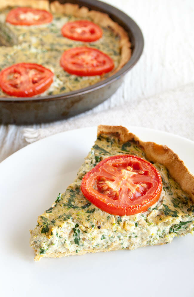 Spinach and Broccoli Vegan Quiche slice with the whole quiche in background.