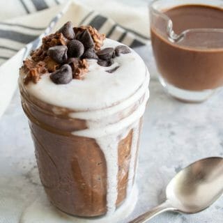 Mint Hot Chocolate Overnight Oats in a mason jar with hot chocolate in the background.