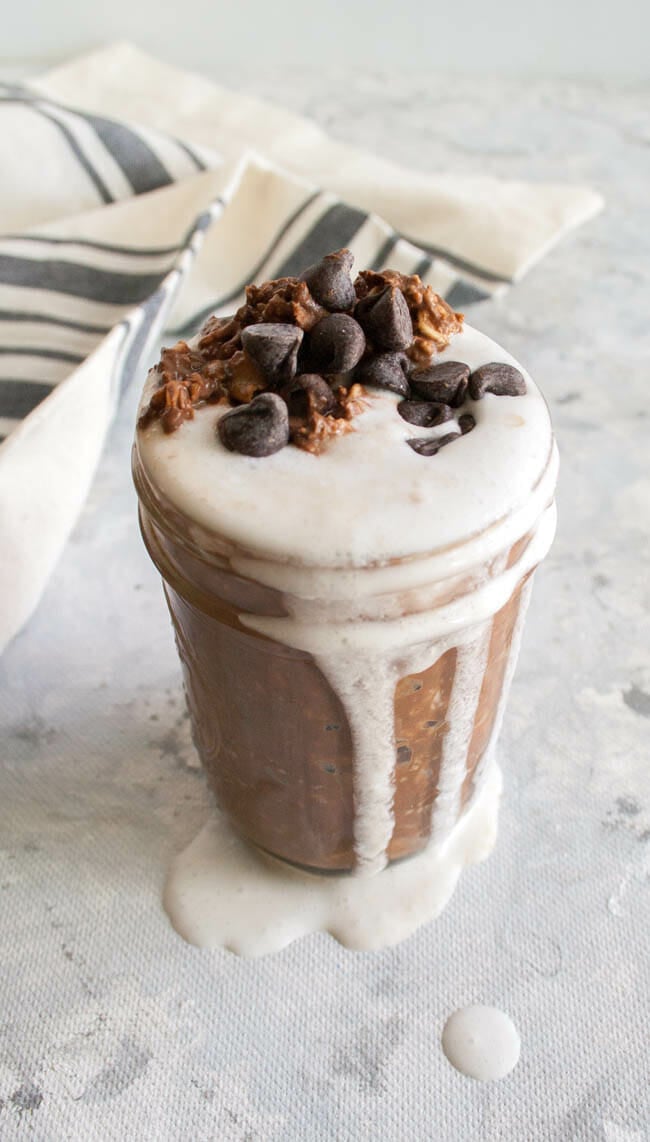 Mint Hot Chocolate Overnight Oats in mason jar with whipped coconut cream dripping down the size.