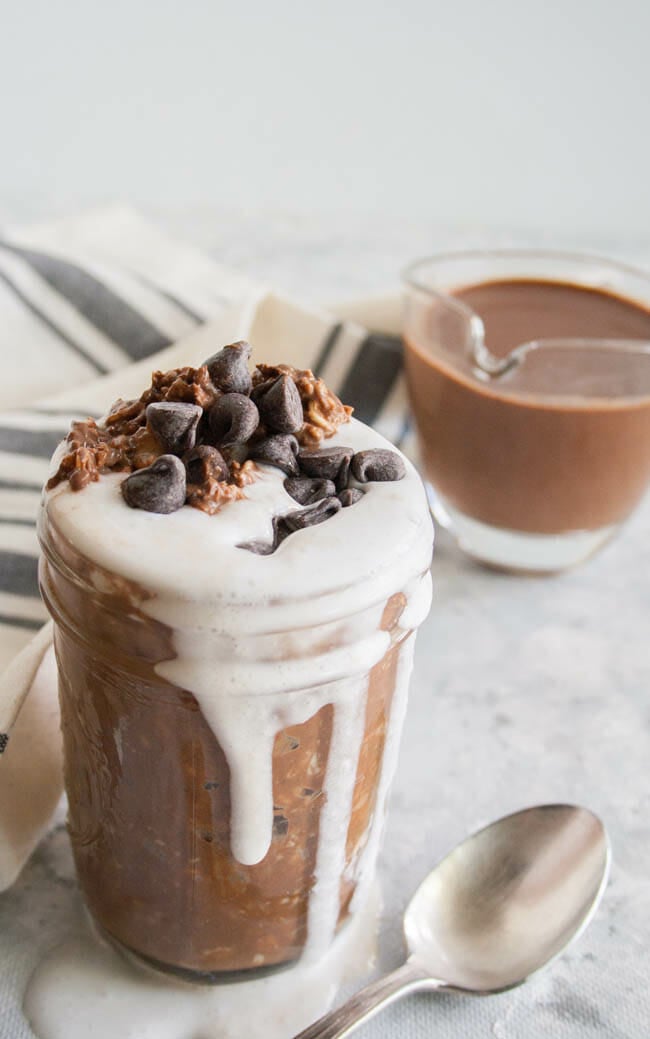 Mint Hot Chocolate Overnight Oats with spoon and mint hot chocolate in the background.