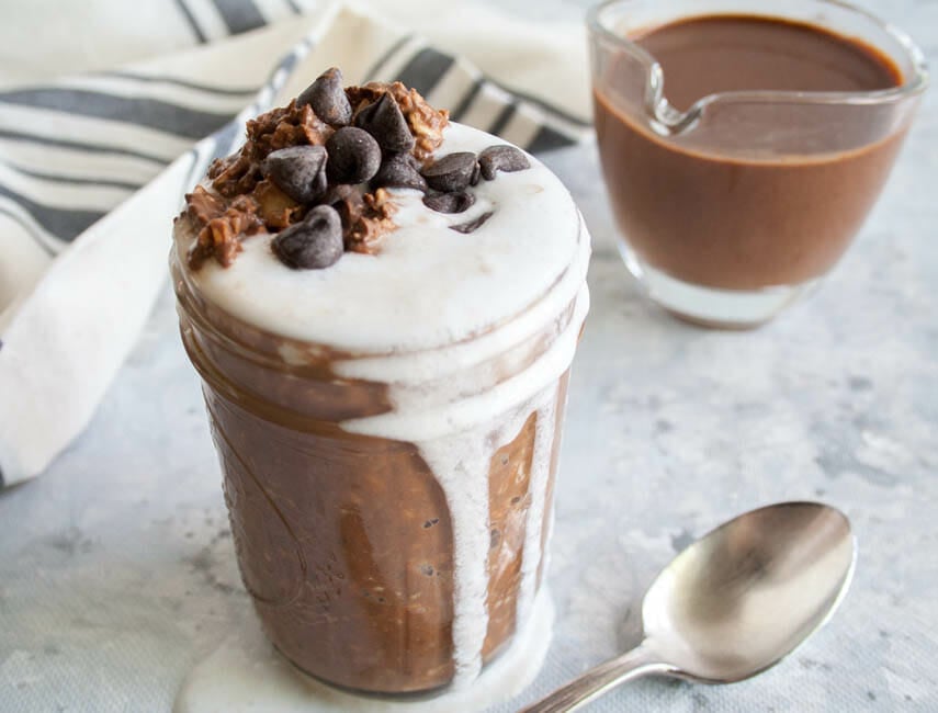 Mint Hot Chocolate Overnight Oats in a mason jar with hot chocolate in the background.
