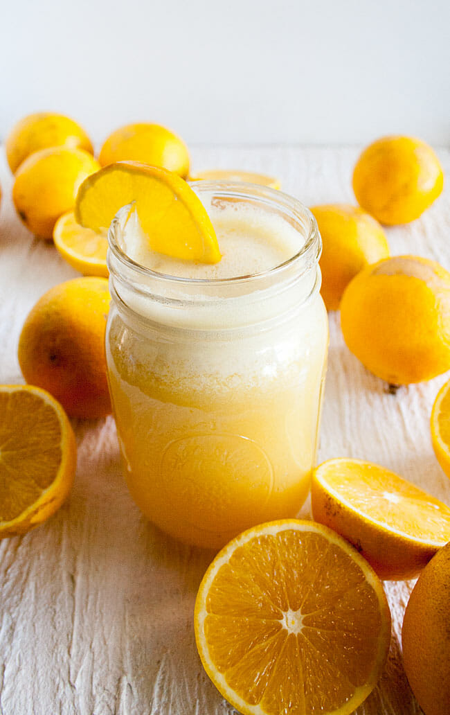 Healthy Homemade Orange Julius in mason jar with oranges all around.