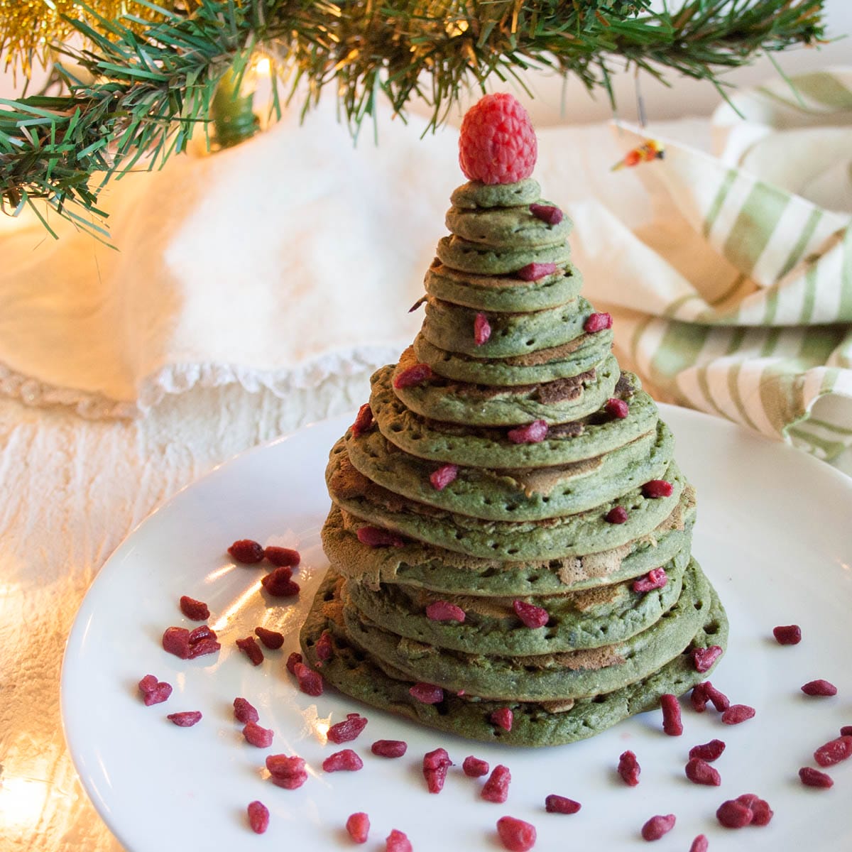 Christmas Tree Pancakes (vegan, gluten free) - This fun green pancake recipe is perfect for a Christmas breakfast or a holiday party. Kids will love them! #christmaspancakes #holidaypancakes Christmas Tree Pancakes on a plate with goji berries.