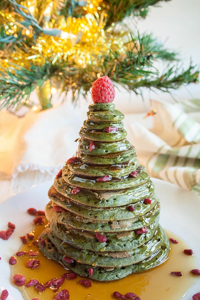 Christmas Tree Pancakes on a plate with maple syrup and goji berries.