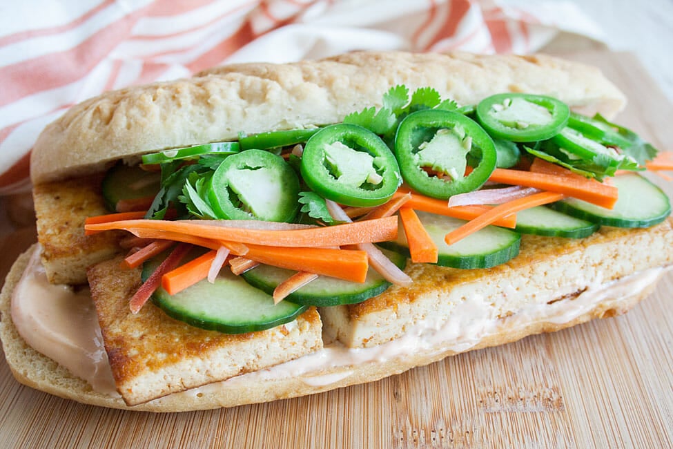 Spicy Tofu Bánh Mì sandwich on cutting board.