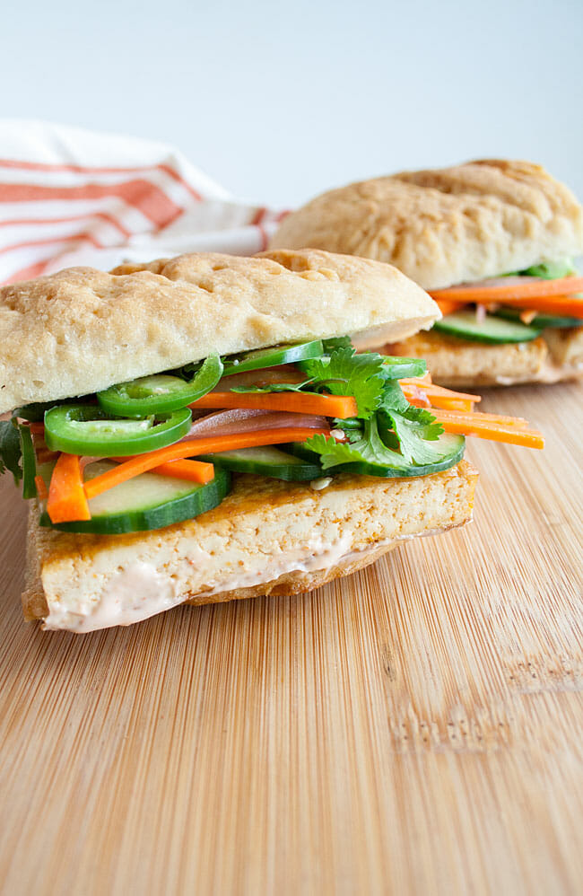 Spicy Tofu Bánh Mì cut in half on a cutting board.