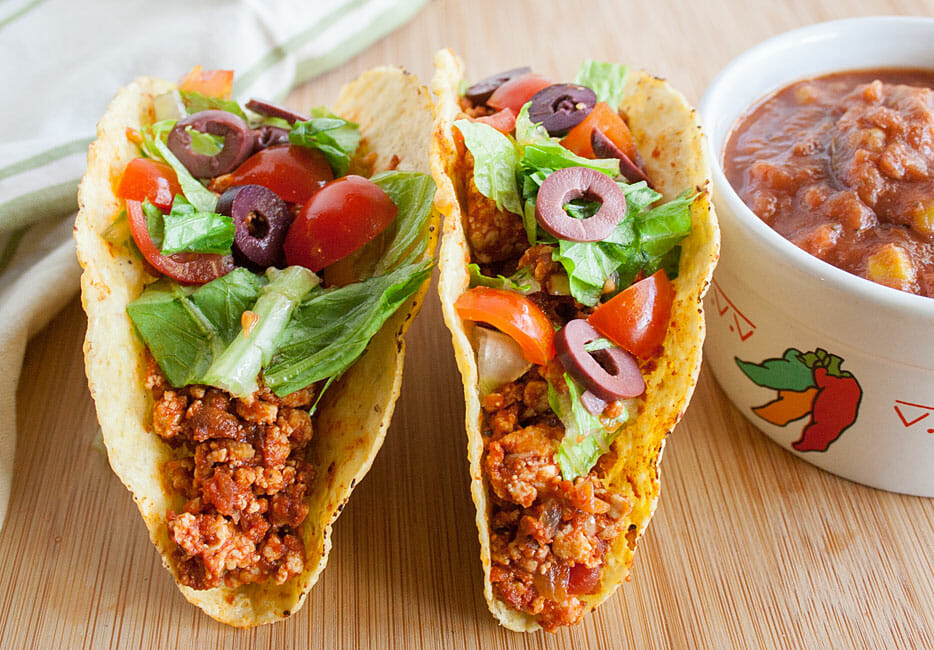 Spicy Tofu Tacos on a cutting board with a ramekin of salsa next to them.