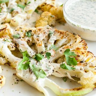 Roasted Cauliflower Steaks with Cilantro Tahini Dressing on a plate.