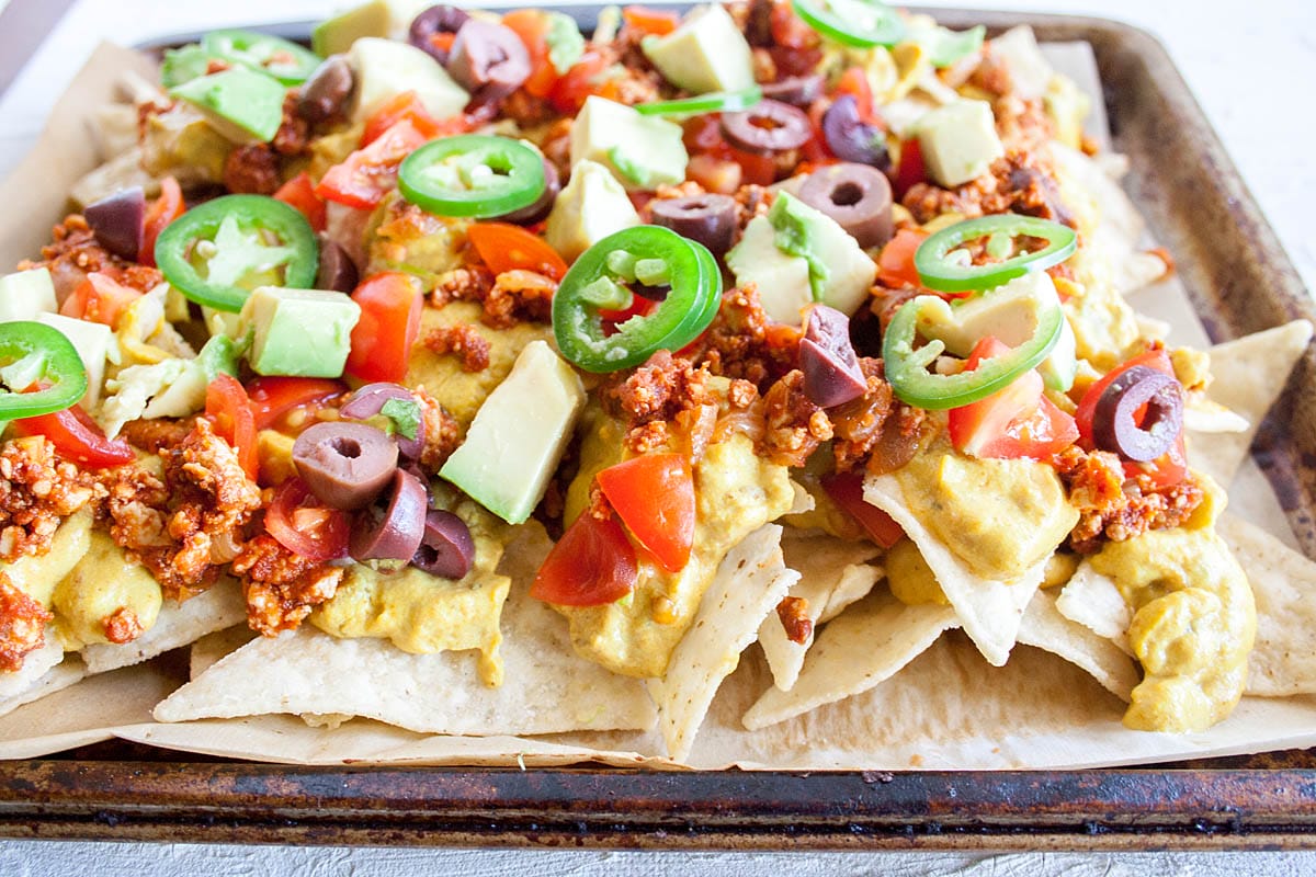 These homemade Vegan Nachos have spicy tofu, vegan nacho cheese sauce and all your favorite toppings baked on a sheet pan. Tofu Nachos on a sheet pan.