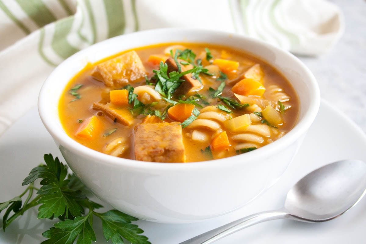 Tofu Noodle Soup (vegan, gluten free) - This healthy soup recipe is pure comfort food in a bowl. Warm up with this easy meal on a cold Winter day. #tofunoodlesoup #vegannoodlesoup Tofu Noodle Soup in a bowl with spoon.