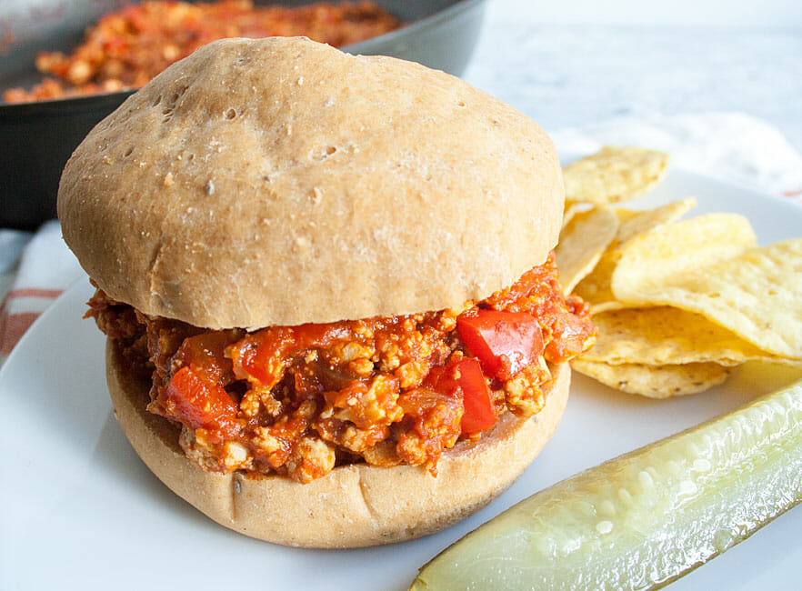 Vegan Sloppy Joes on a plate with chips and a pickle.