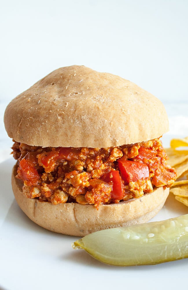 Vegan Sloppy Joes on a plate with dill pickle and tortilla chips close up. 