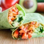 Thai Veggie Wrap cut in half on a cutting board.