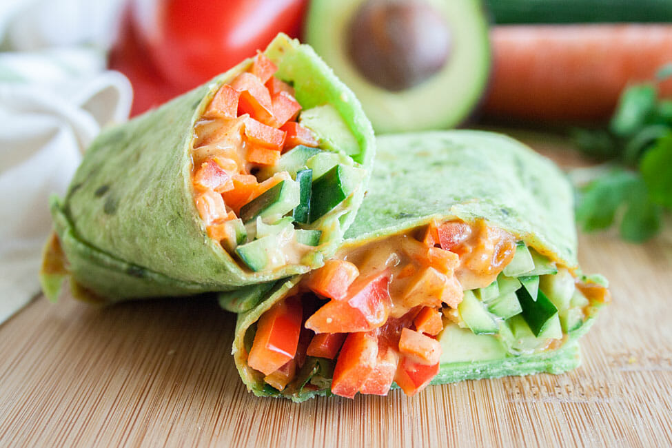 Veggie Wrap sliced in half on a cutting board.