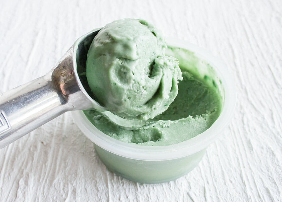 Mint ice cream being scooped out of container.