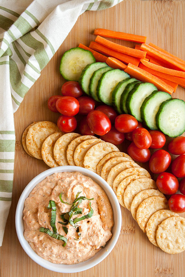 Dip with vegetables on cutting board.