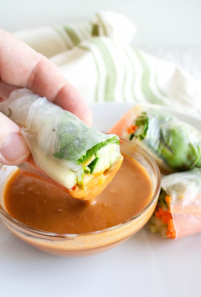 Spring Roll being dipped in Peanut Sauce. 