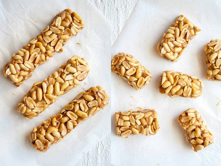 Homemade Payday Candy Bars with layer of peanuts in jumbo size and small sized on parchment paper.