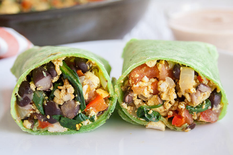 Burrito sliced in half on a plate.