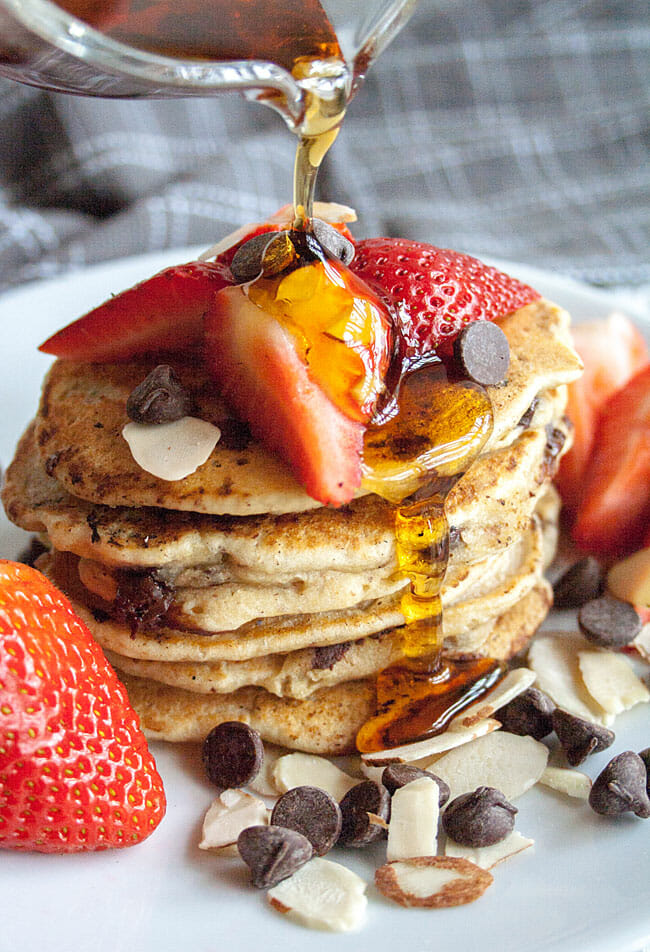 Vegan Chocolate Chip Pancakes with syrup being poured over them