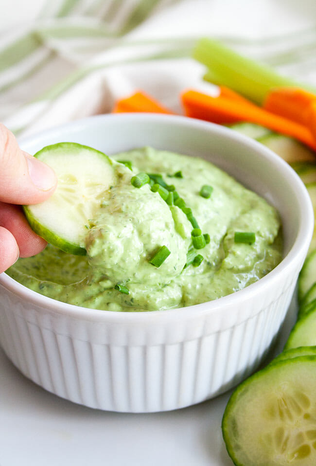 Green Goddess Dip with cucumber being dipped.