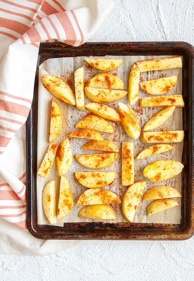 French Fries on sheet pan before baking with seasoning on top.